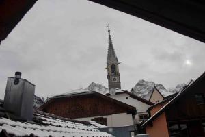 eine Kirche mit einem Uhrturm mit schneebedeckten Dächern in der Unterkunft Ferienwohnung Scaletta in Scuol