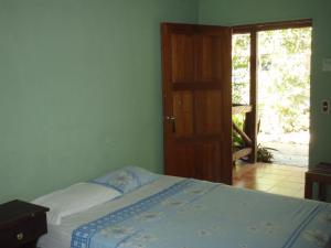Schlafzimmer mit einem Bett und einer Tür zu einer Terrasse in der Unterkunft Guest house Posada Ixchel in El Remate