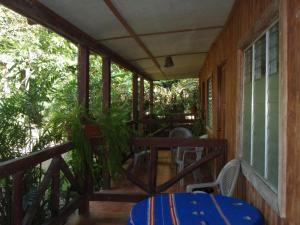 un porche de una casa con mesa y sillas en Guest house Posada Ixchel, en El Remate