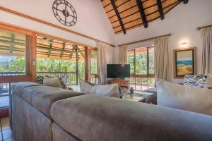 - un salon avec un lit, une télévision et des fenêtres dans l'établissement Kruger Park Lodge Unit No. 241, à Hazyview