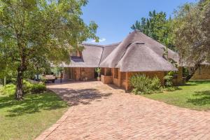une maison en briques avec un toit de chaume et une allée. dans l'établissement Kruger Park Lodge Unit No. 241, à Hazyview
