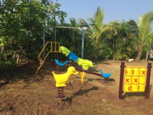a playground with a slide and a swing at Windchime Cottages in Alibaug