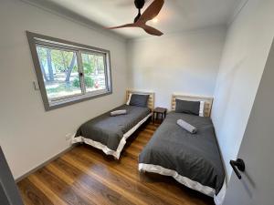 two beds in a room with a window at Luxury Holiday Unit 8min walk to Town Center with Boat Parking in Mallacoota