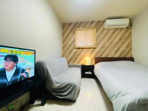 1 Schlafzimmer mit 2 Betten und einem Flachbild-TV in der Unterkunft Namba Tsutenkaku High Class Villa in Osaka