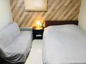 ein Schlafzimmer mit 2 Betten und einem Tisch mit einer Lampe in der Unterkunft Namba Tsutenkaku High Class Villa in Osaka
