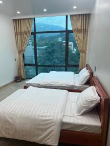 2 Betten in einem Zimmer mit einem großen Fenster in der Unterkunft Minh Vân Hostel in Ha Giang