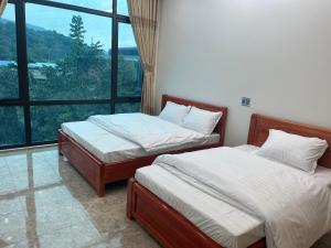 Duas camas num quarto com uma janela grande em Minh Vân Hostel em Ha Giang