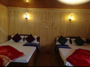 twee bedden in een kamer met houten wanden bij Snow White Holiday Inn Homestay in Kalimpong