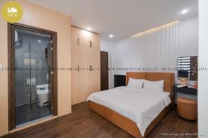 a bedroom with a large bed and a bathroom at MCK Homestay Dalat - Can ho 104 in Ấp Ða Lợi