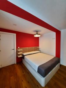 sypialnia z dużym łóżkiem i czerwoną ścianą w obiekcie Sunshiny Costa del Sol - BEACH APARTMENT w mieście Fuengirola +30 zdjęć