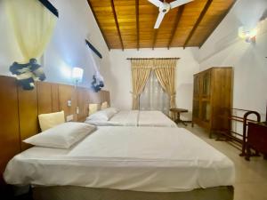 a bedroom with two white beds and a wooden ceiling at Hikka Paradise Guest House in Hikkaduwa +27 photos