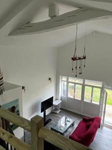 a living room with a red couch and a table at Equizen33 maison zen et ressourçante in Saint-Mariens