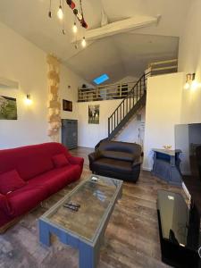 a living room with a red couch and a table at Equizen33 maison zen et ressourçante in Saint-Mariens