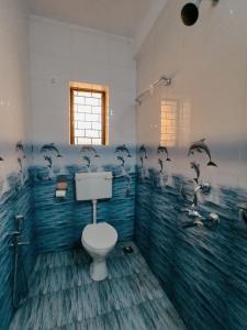 a bathroom with a toilet and dolphins on the wall at CASA FIESTA guest House in Palolem