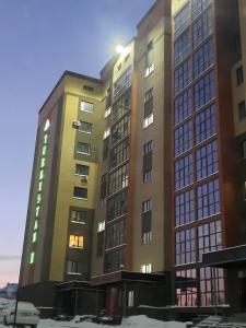 un edificio alto con las luces encendidas en Апартаменты на Кенесары 83, en Kokshetau