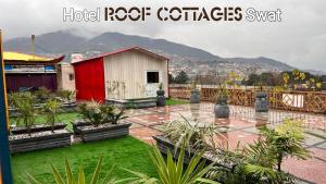a garden with a red and white shed and plants at Hotel Roof Cottages Swat in Swat
