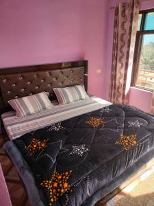 a bedroom with a bed with a black quilt on it at Pandava's Cafe & Stay in Chopta