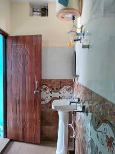 uma casa de banho com uma porta de madeira e um lavatório em Pandava's Cafe & Stay em Chopta