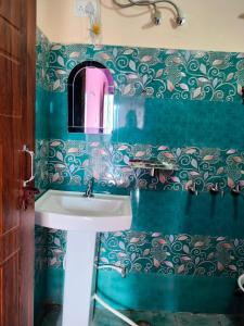 a bathroom with a sink and a green tiled wall at Pandava's Cafe & Stay in Chopta