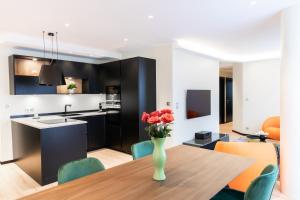 a kitchen and dining room with a vase of flowers on a table at Suite Romanée 6 personnes vue Cathédrale 2 Places de parking in Dijon