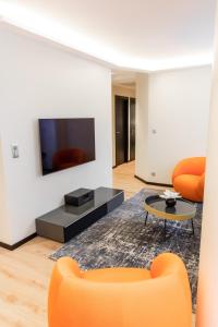 a living room with orange furniture and a flat screen tv at Suite Romanée 6 personnes vue Cathédrale 2 Places de parking in Dijon