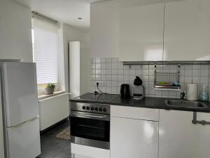 a white kitchen with a stove and a sink at Ferienwohnung Falkenstr. in Enger
