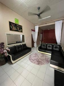 a living room with two black couches and a rug at MIA FAMILIA HOMESTAY in Cukai