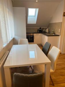 - une cuisine avec une table et des chaises blanches dans l'établissement Ferienwohnung Alpina, à Feldkirch