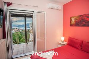 Schlafzimmer mit einem roten Bett und einem Balkon in der Unterkunft Helmata Villa with privecy in Argostoli