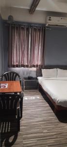 索拉普的住宿－Hotel Ashirwad, Solapur，一间卧室配有一张床、一张桌子和窗帘
