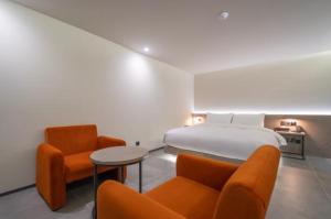 Habitación de hotel con 1 cama y 2 sillas de color naranja en Hotel TARA en Seúl