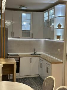 a kitchen with white cabinets and a sink and a table at Central Luxury Suites in Bijeljina