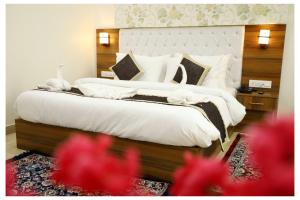 ein Schlafzimmer mit einem großen Bett mit weißer Bettwäsche und Kissen in der Unterkunft Hotel Signature Prime Vaishali Nagar Jaipur in Jaipur