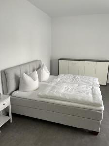 uma cama com lençóis brancos e almofadas num quarto em Ferienhof Elbaue em Schönebeck