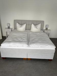 a bed with white pillows on it in a room at Ferienhof Elbaue in Schönebeck