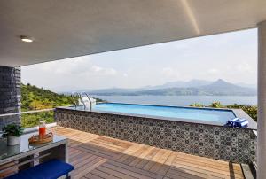 a swimming pool on a patio with a view of the water at SaffronStays Kaia Waters by Kosha Villas, Pawna - Greek style villa with panoramic view of Pawna lake in Kolvan