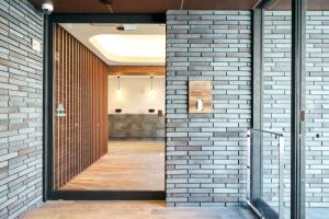 uma parede de tijolos com uma porta que leva a um corredor em Rakuten STAY Kokura Station Standard Triple Room em Kitakyushu