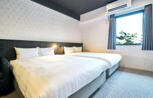 een slaapkamer met een groot wit bed en een raam bij Rakuten STAY Kokura Station Standard Twin Room in Kitakyushu