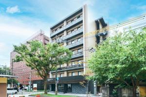 een hoog gebouw met bomen ervoor bij Rakuten STAY Kokura Station Standard Twin Room in Kitakyushu