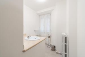 ein weißes Badezimmer mit einem Waschbecken und einem Heizkörper in der Unterkunft Palazzetto Vittoria - F&L Apartment in Brescia
