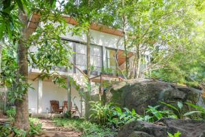 ein Haus in den Bäumen mit einem großen Felsen in der Unterkunft Thalassa Dive & Wellbeing Resort Manado in Manado