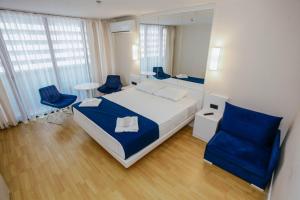 a bedroom with a large bed and blue chairs at Orbi City Sea View - Special Category in Batumi