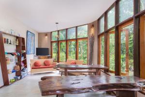 Thalassa Dive & Wellbeing Resort Manado في مانادو: غرفة معيشة مع نوافذ كبيرة وطاولة