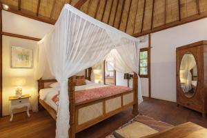 een slaapkamer met een hemelbed en een spiegel bij Villa Terra in Gili Trawangan