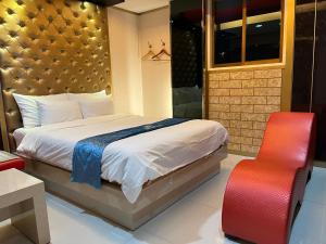 a bedroom with a bed and a red chair at Queen Drive-In Motel in Jeju