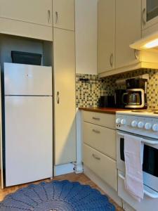 eine Küche mit weißen Schränken und einem weißen Kühlschrank in der Unterkunft Huoneisto Jalkarannassa in Lahti