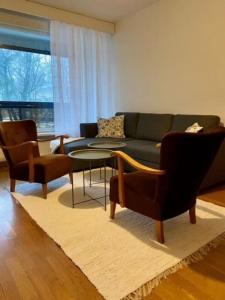 ein Wohnzimmer mit einem Sofa, einem Tisch und Stühlen in der Unterkunft Huoneisto Jalkarannassa in Lahti