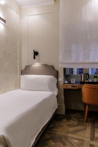 a bedroom with a large white bed and a desk at Hotel Smeraldo in Rome