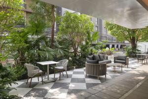 a patio with tables and chairs and trees at PARKROYAL Suites Bangkok - SHA Plus Certified in Bangkok