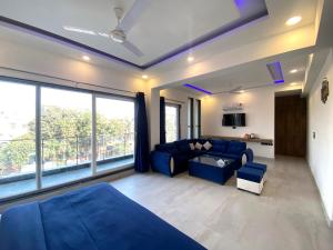 sala de estar con sofá azul y ventana grande en The Metro Stay By F9 Hotels-Near Sector 18 Metro Station Noida en Noida